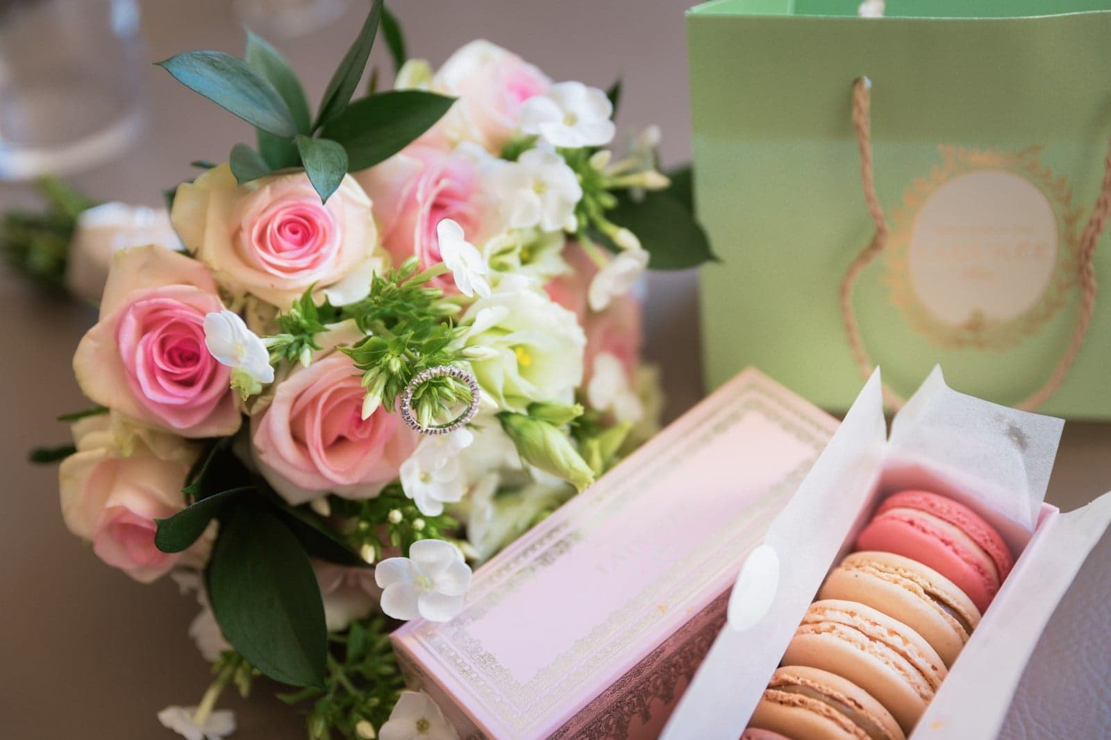 Caixa de macarons ao lado de um buquê de rosas